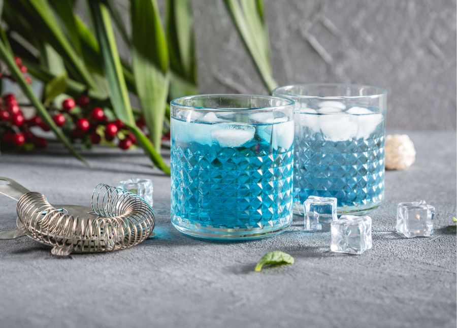 Tropisk Blue Lagoon cocktail med blå curaçao og vodka i et hurricane glas med is
